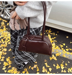 Detail of dark brown leather Boston bag featuring a dual zipper and glossy finish
