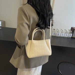 Quilted cream crossbody bag with top handle and adjustable strap in minimalist style