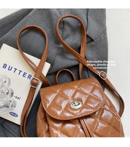 Détail du sac à dos en cuir matelassé marron avec fermoir rotatif argenté sur veste