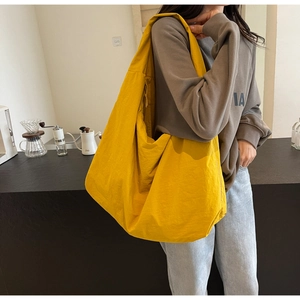 Close-up of bright yellow lightweight nylon hobo bag on a model in a cafe setting