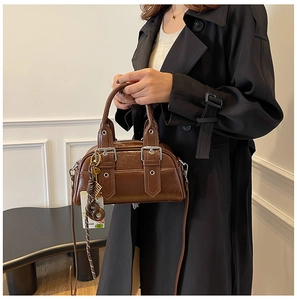 Détail d'un sac bandoulière marron foncé rétro avec boucles argentées et pendentifs