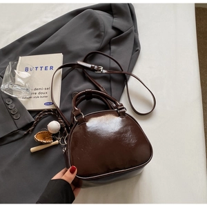 Detail of a shiny dark brown vintage bowling bag with a baseball glove keychain charm