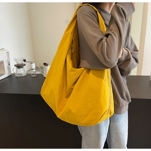 Detailed view of a yellow pleated oversized shoulder bag showing soft nylon fabric texture