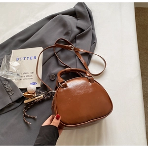 Detail of vintage brown bowling bag with glossy texture and baseball charm on white fabric
