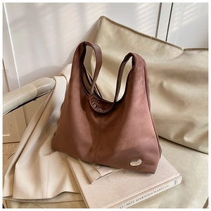 Detailed macro view of brown suede shoulder bag with silver metallic logo on leather chair