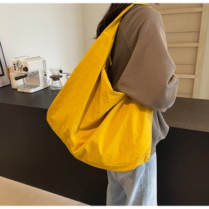 Close-up of yellow wrinkled nylon shoulder bag showing light fabric texture and wide strap