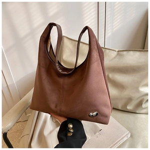 Detail of a brown matte suede tote bag with a unique silver metal buckle and wide strap