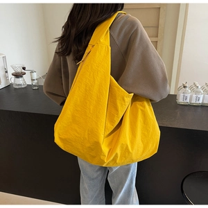 Rear view of a model wearing the large yellow puffer shoulder bag in a cafe setting
