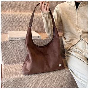 Close-up of a large brown suede hobo bag showing thick soft texture and leather handle