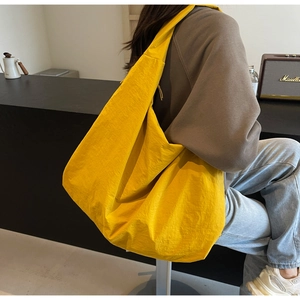 Detailed view of lightweight yellow nylon shoulder bag showing pleated texture and large capacity