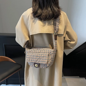 Sac cabas à motif pied-de-poule avec fermoir doré porté sur un trench-coat