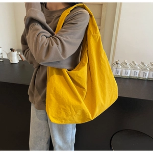 Detailed view of yellow lightweight parachute fabric hobo bag on a model shoulder