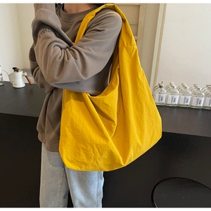 Close-up detail of oversized bright yellow nylon tote bag with a natural crinkled texture