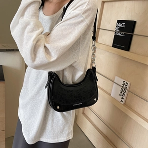 Minimalist black patent leather crescent shoulder bag with silver chain and studs