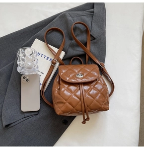 Vue détaillée du mini sac à dos marron matelassé avec fermoir rotatif sur une veste