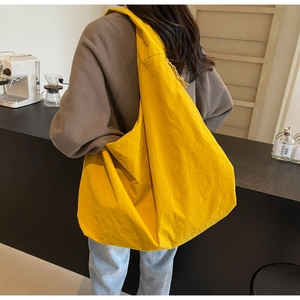 Detail of lemon yellow quilted puff bag made of lightweight parachute fabric on a shoulder