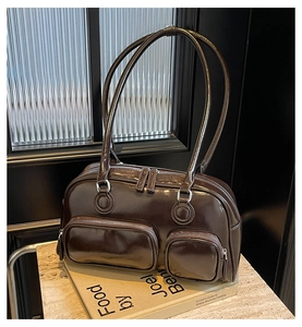Detail view of glossy chocolate leather bowling bag with three zip pockets and silver hardware