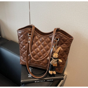 Close-up of brown quilted tote bag with diamond pattern and cute rabbit charm detail