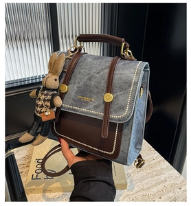 Detailansicht der Kontrastnähte und des braunen Leders am grauen Denim-Rucksack