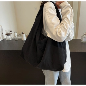 Black lightweight nylon hobo bag shown in a lifestyle scene with a white hoodie