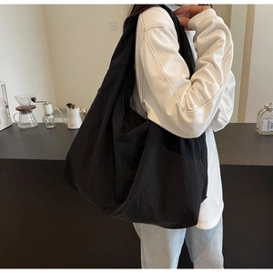 Black lightweight puff hobo bag made of glossy nylon fabric shown in a cafe setting
