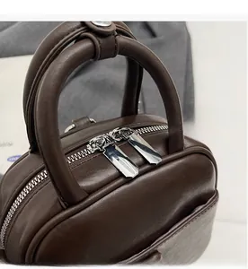 Detail of smooth metal double zippers and flexible leather texture on dark brown handbag