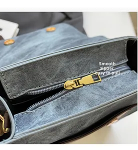 Détail de la fermeture éclair dorée et du tissu denim gris sur le sac à dos de voyage