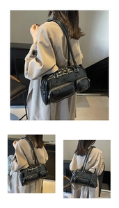 Detail of black oil-waxed leather shoulder bag featuring dual front zipper pockets