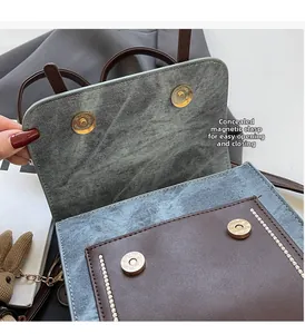 Détail d'un sac à rabat bicolore montrant les boutons de fermeture magnétique dorés