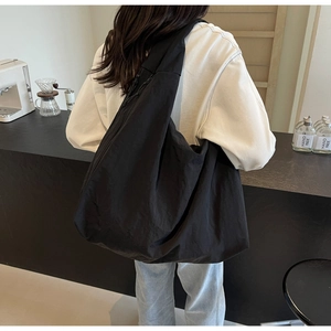 Detail view of a black oversized puffy shoulder bag in lightweight parachute fabric