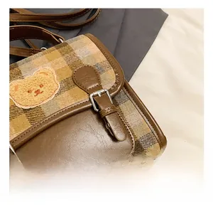 Detail of vintage patchwork bag with metallic buckle and embroidered bear patch