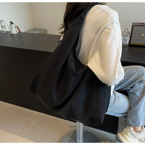Detail of a large black nylon puff bag with matte texture and minimalist slouchy design