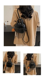 Detail of black mini PU leather backpack with bear charm and scarf detail in a cafe