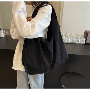 Detailed view of lightweight black puffer tote bag with side drawstring worn by a model