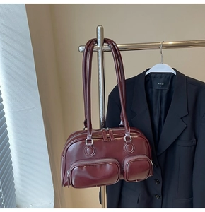 Deep red vintage bowling bag with front pockets styled on a hanger with a black blazer
