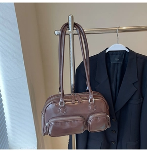 Detail of vintage brown shoulder bag showing dual front zip pockets and oily leather texture