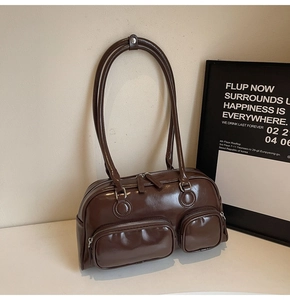 Detail of dark brown glossy bowling bag with double zipper pockets on minimalist surface