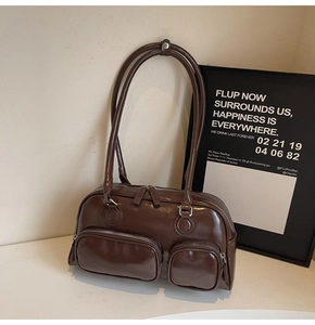 Close-up of dark brown glossy faux leather shoulder bag with functional dual zippers