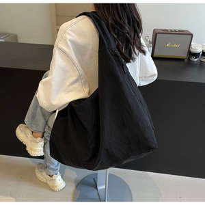 Detail of a black oversized shoulder tote bag in nylon fabric with zipper closure