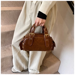 Close-up of vintage brown bowling bag with gold hardware, rivets, and textured faux leather