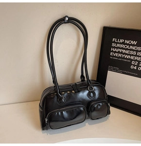 Detail view of black oiled leather square shoulder bag with multiple functional zip pockets
