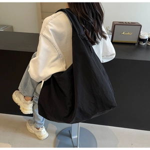 Detail of black puffer bag with wide strap and lightweight parachute fabric texture
