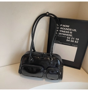 Close-up of black oil-wax leather shoulder bag featuring dual zipper pockets and silver hardware