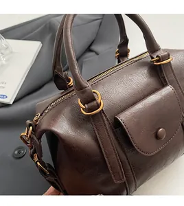 Close-up of retro brown leather texture and golden hardware on Boston pillow bag