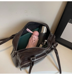 Spacious interior of chocolate oil wax leather bag holding tablet, umbrella and perfume