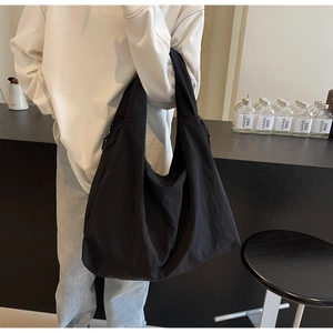 Detail of lightweight black puffer tote bag with adjustable side drawstrings and nylon finish