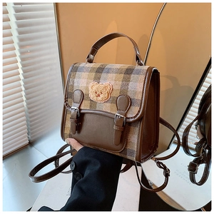 Close-up of retro plaid mini backpack featuring a plush bear patch and leather straps