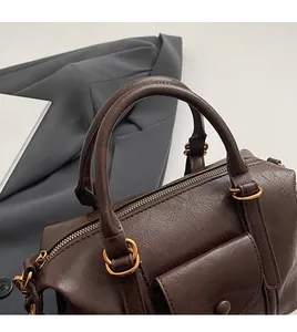 Detail of round handles and gold hardware on a dark brown vintage Boston handbag