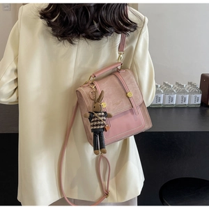 Rosa Patchwork-Rucksack mit Hasen-Anhänger, getragen an einem Model im beigen Anzug