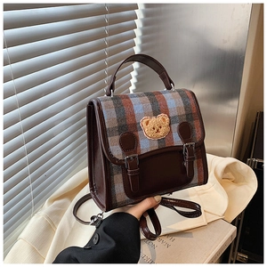 Dettaglio dello zaino vintage a quadri con cinturini in pelle e toppa a forma di orso